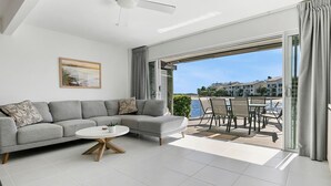 A modern living room with a grey sofa, a white coffee table, and a painting on the wall. - Driftwood 5 Noosaville (Noosaville)