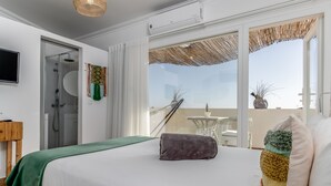Ein Hotelzimmer mit Bett, einem Fenster mit Blick, einer Dusche und einem kleinen Tisch mit Pflanze.