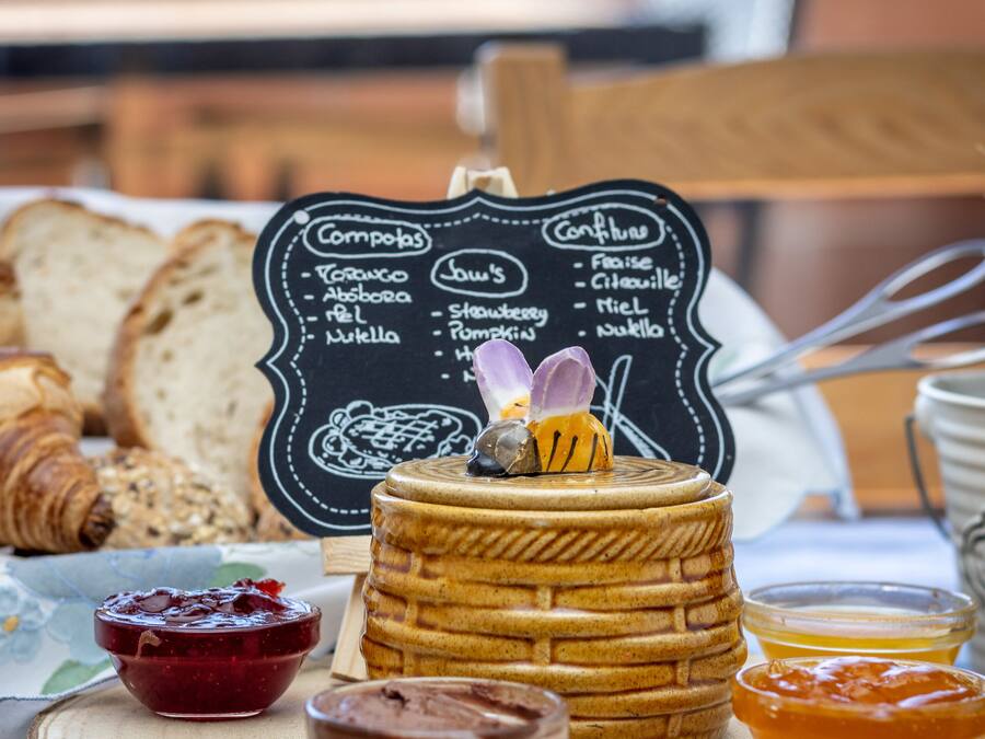 A wooden board with a waffle, two small bowls of jam, and a honey dipper.