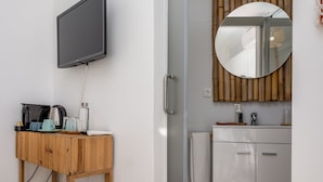 Ein modernes Badezimmer mit einem Holzlagerfläschchen, einem Spiegel und einem an der Wand befestigten Fernseher.