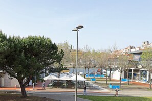 A park with outdoor seating, a lamp post, and a building with a modern design. - FLH Gaia Wine Cellars Flat (Vila Nova de Gaia)