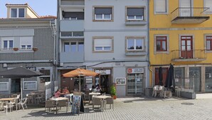 Ein Gebäude mit mehreren Balkonen und einem Café mit Außenplätzen.