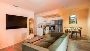Un salon comprenant un canapé, une table basse, un téléviseur et un coin repas avec des chaises et une table.