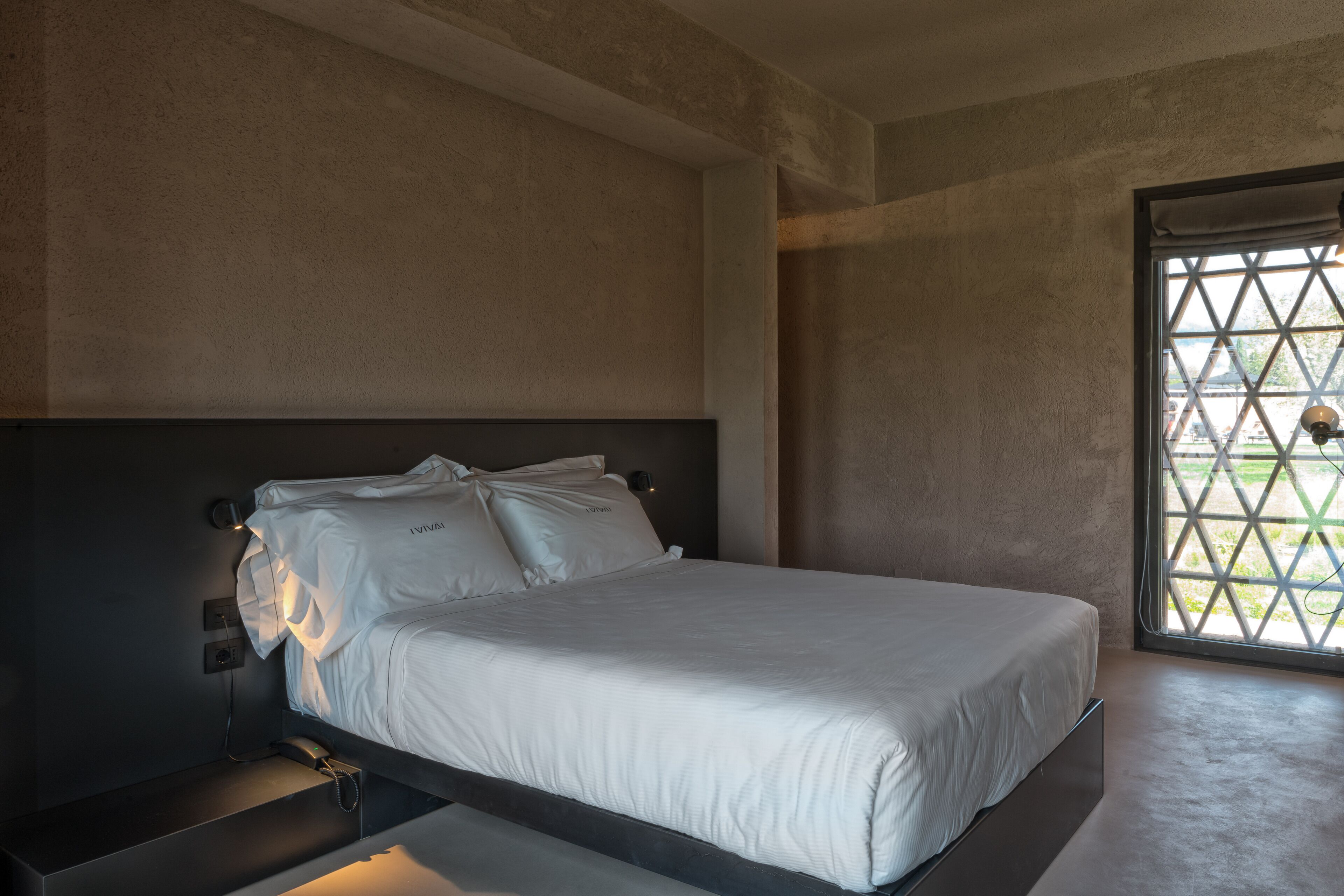 Een moderne slaapkamer met een groot bed, een nachtkastje en een raam met uitzicht.