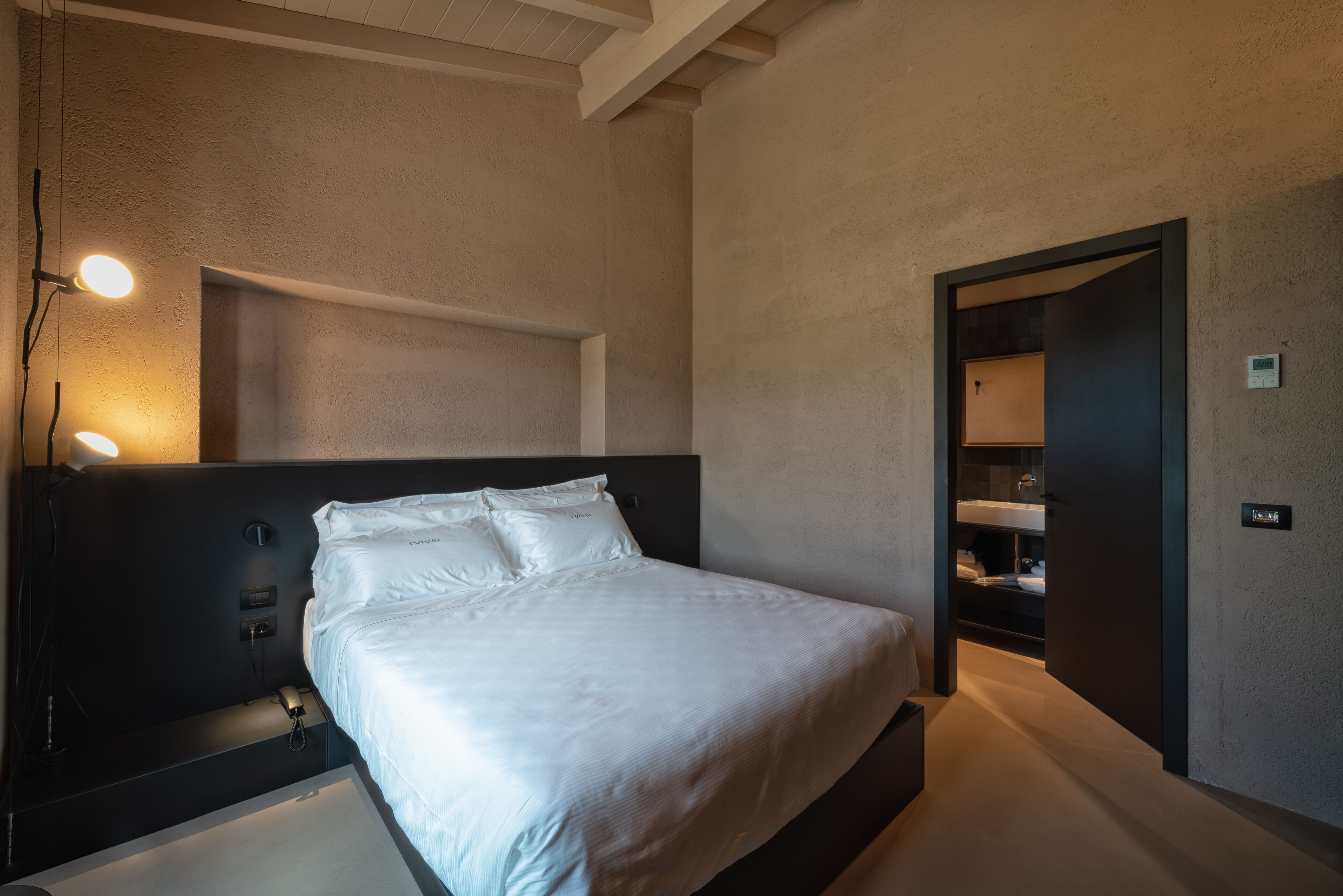 A modern bedroom with a large bed, bedside lamps, and a built-in wardrobe.