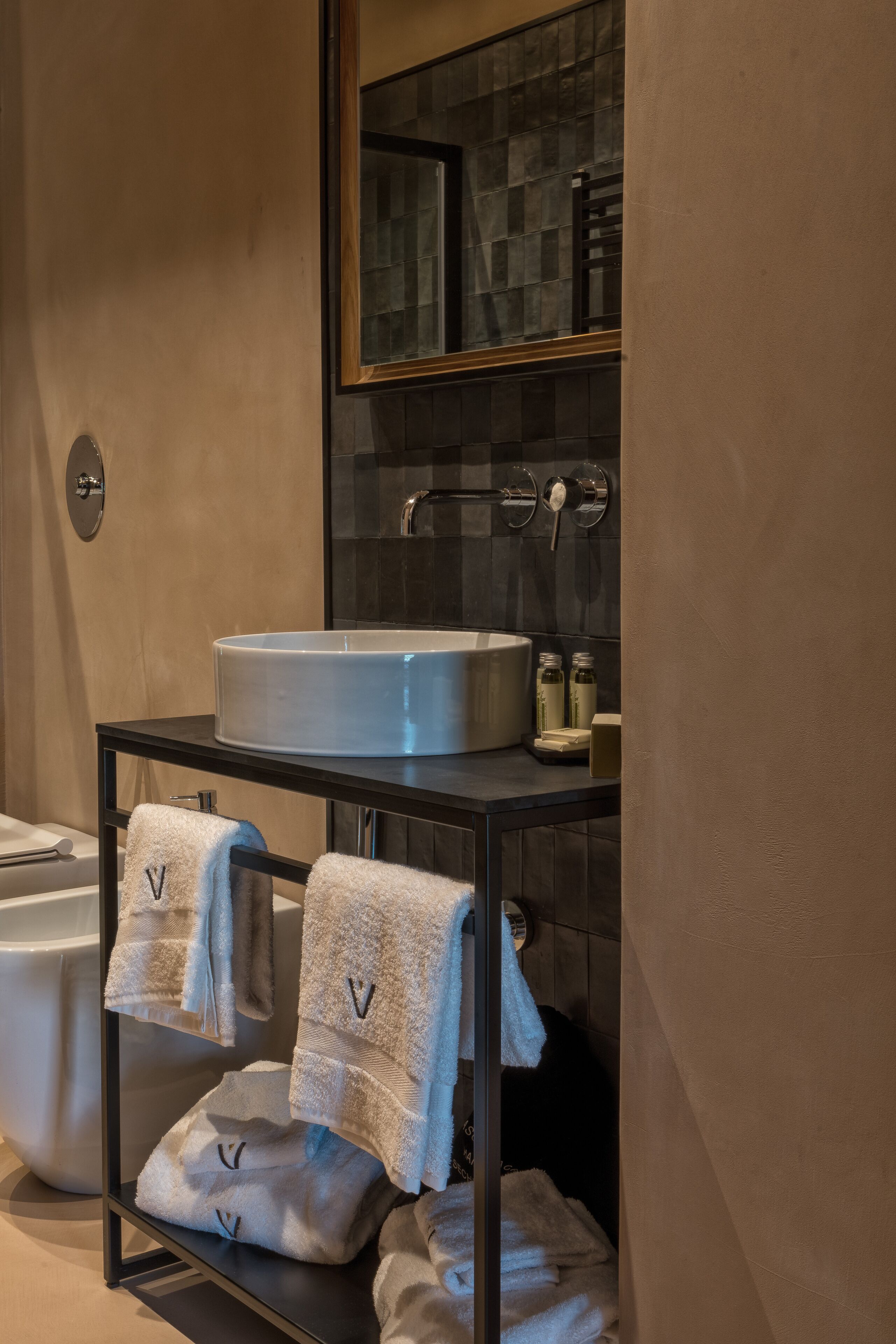Une salle de bain moderne avec un grand lavabo, un miroir et un porte-serviettes avec des serviettes.