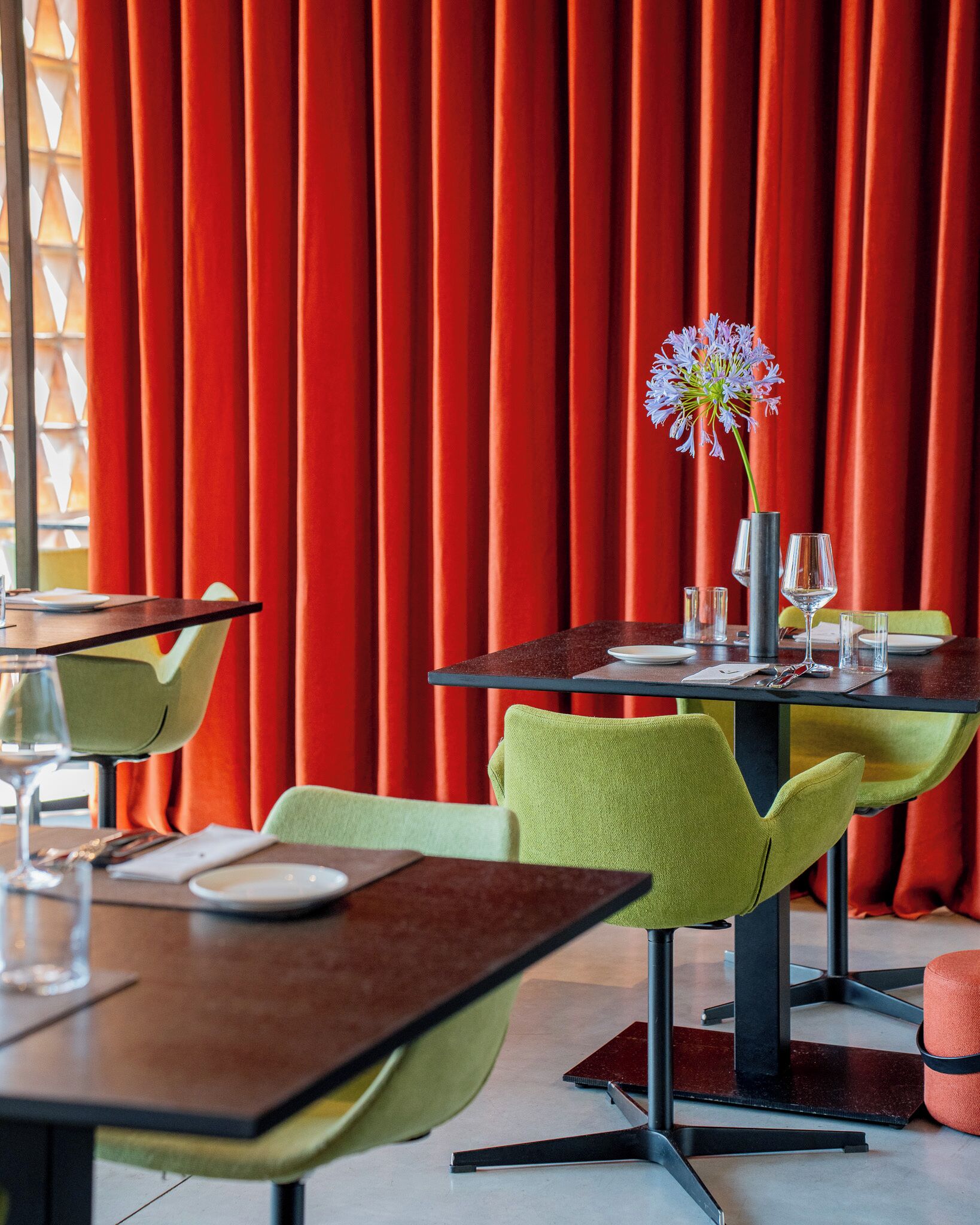 Un restaurante con cortinas rojas, sillas verdes y una mesa lista para comer.