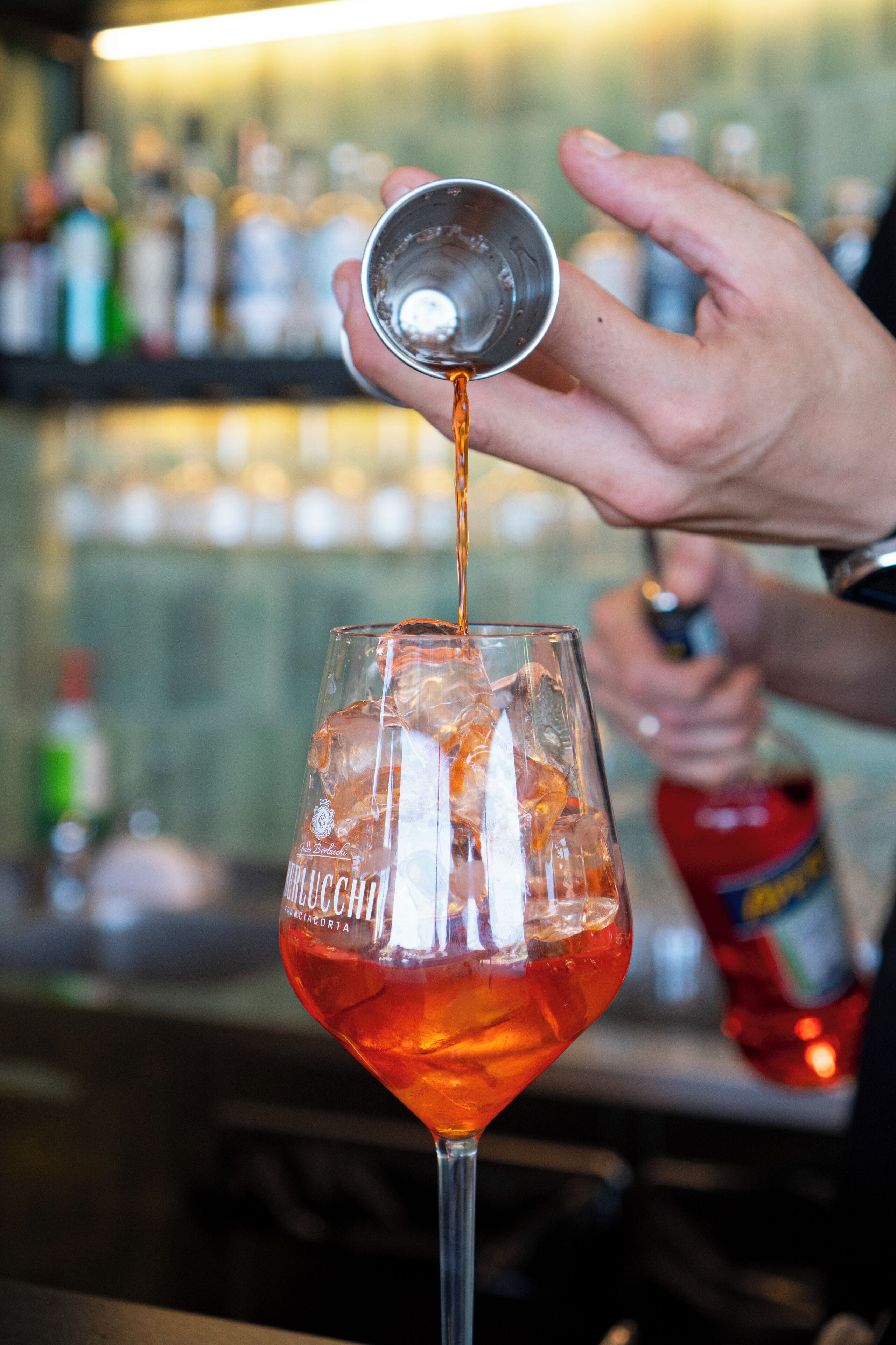 Ein Barkeeper gießt ein Getränk in ein Glas mit dem Aufdruck 'Perrier'.