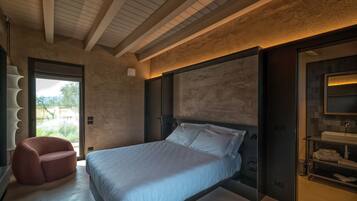 Ein modernes Schlafzimmer mit einem großen Bett, einer Sitzecke und einem Badezimmer mit Waschtisch und Regalen.