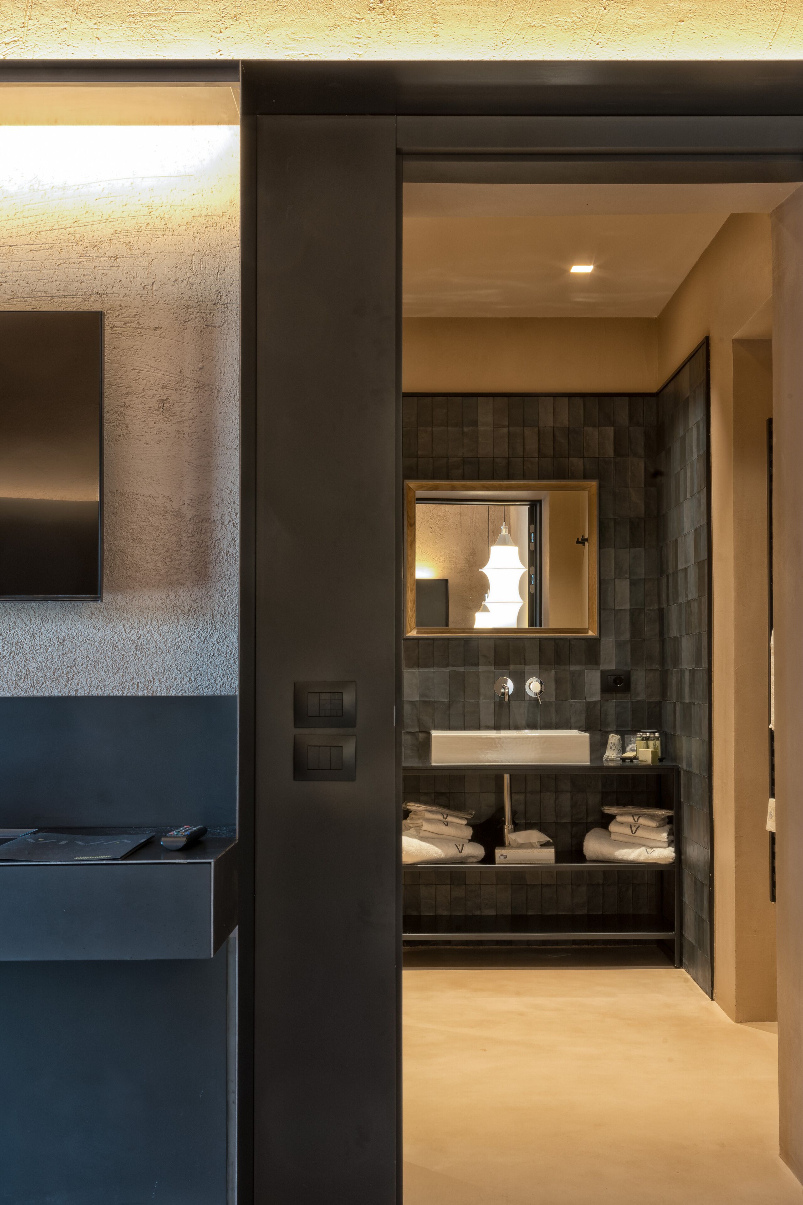 Un baño moderno con un espejo grande, un lavamanos y un perchero para toallas.