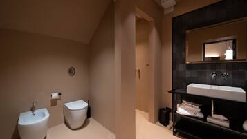 A modern bathroom with a bidet, toilet, and a large sink with a mirror above it.
