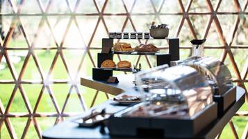 Una disposición de buffet con diversos alimentos y condimentos, frente a un fondo con un diseño geométrico.