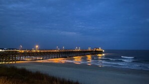 Eine Steg, der sich bis ins Meer erstreckt, beleuchtet bei Nacht.