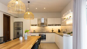 Una cocina moderna con una mesa de comedor de madera, sillas negras, horno empotrado y refrigerador blanco.