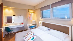 Habitación de hotel con cama, escritorio, silla y ventana con vistas a la ciudad.
