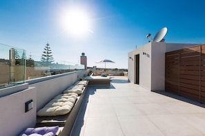 A rooftop terrace with seating, a satellite dish, and a view of the cityscape.