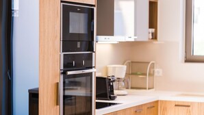 Een moderne keuken met roestvrijstalen apparatuur, houten kastjes en een wit aanrecht.