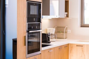 A modern kitchen with stainless steel appliances, wooden cabinets, and a white countertop. - Villa Amelia I Free Mini van Private Pool (Chania)
