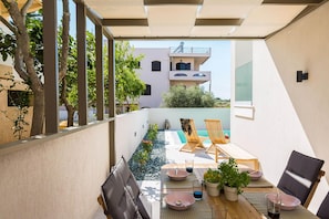 Een modern terras buiten met een zwembad, houten meubels en potplanten.