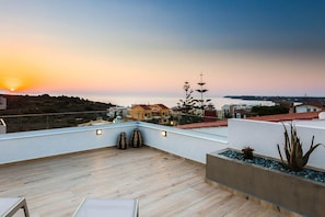 A rooftop terrace with a view of the sunset over the sea, wooden flooring, and a few potted plants. - Villa Amelia I Free Mini van Private Pool (Chania)