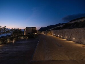 A wooden pathway leading to a building with a stone wall on one side and a view of the sea on the other. - Villa Vista I Free Heated Pool Dazzling Seaview (Kissamos)