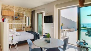Quarto de hotel moderno com cama, escrivaninha, cadeira, mesa redonda e varanda com vista.