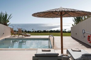 A pool area with lounge chairs, a thatched umbrella, and a view of the ocean. - Villa Vista I Free Heated Pool Dazzling Seaview (Kissamos)