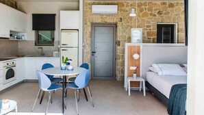 Quarto de hotel compacto com cozinha compacta, área de jantar, cama e banheiro.