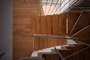 A modern staircase with wooden steps and metal railings, leading to a higher floor.