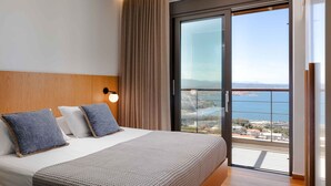 A hotel room with a large bed, a view of the sea, and a sliding glass door to the balcony. - Omnia Villa I - Heated Pool Stunning Seaview (Chania)