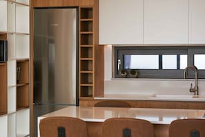 A modern kitchen with a stainless steel refrigerator, wooden shelving, a built-in sink, and a window above the counter. - Omnia Villa I - Heated Pool Stunning Seaview (Chania)