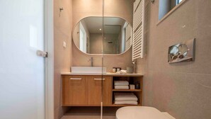 A modern bathroom with a wooden vanity, a large mirror, a toilet, and a towel rack. - Villa Mare I Free Heated Pool Infinite Blue (Kissamos)