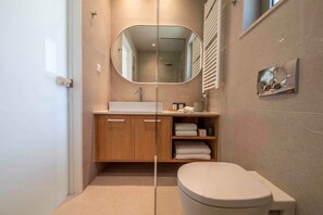 A modern bathroom with a wooden vanity, a large mirror, a toilet, and a towel rack. - Villa Mare I Free Heated Pool Infinite Blue (Kissamos)