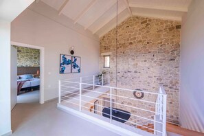Un cuarto estilo loft con pared de piedra, barandal blanco y cama con vistas.