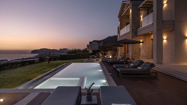 A modern poolside area with lounge chairs, a pool, and a view of the sea at dusk. - Villa Mare I Free Heated Pool Infinite Blue (Kissamos)