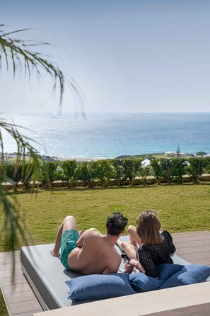 Una pareja descansando en una tumbona con vistas al océano.