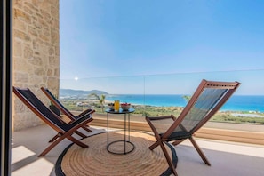 Un balcón con dos sillas, una mesa y vistas al mar.