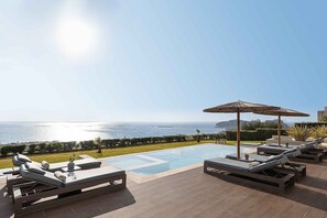A poolside area with lounge chairs, a small pool, and a view of the sea. - Villa Mare I Free Heated Pool Infinite Blue (Kissamos)