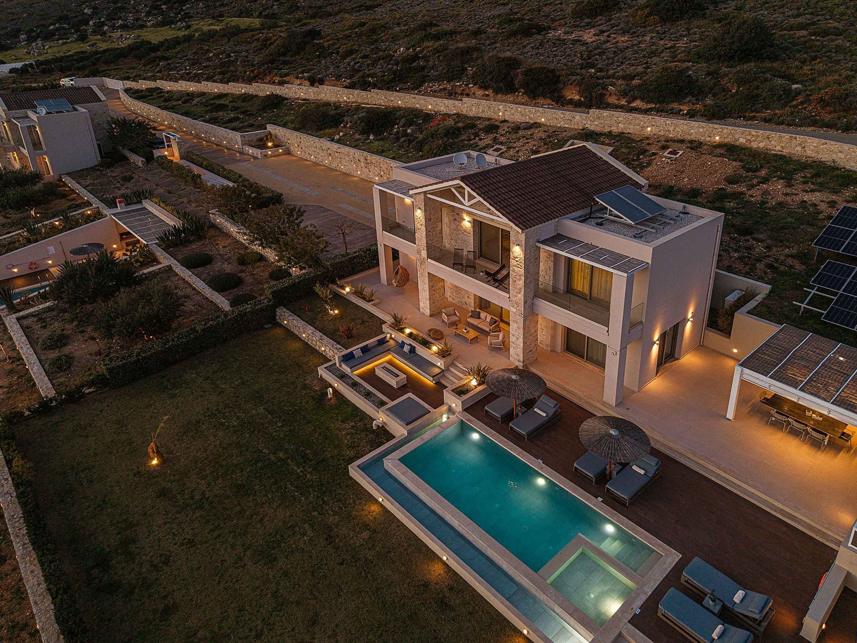 Een modern huis met twee verdiepingen, een zwembad, terras en zonnepanelen.