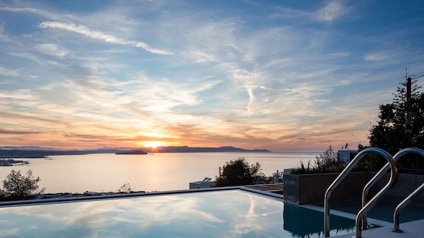Une piscine offrant une vue sur le coucher de soleil au-dessus d’une étendue d’eau.