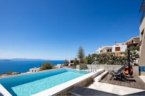 Une piscine avec vue sur la mer, une bouée de sauvetage et une terrasse en bois.
