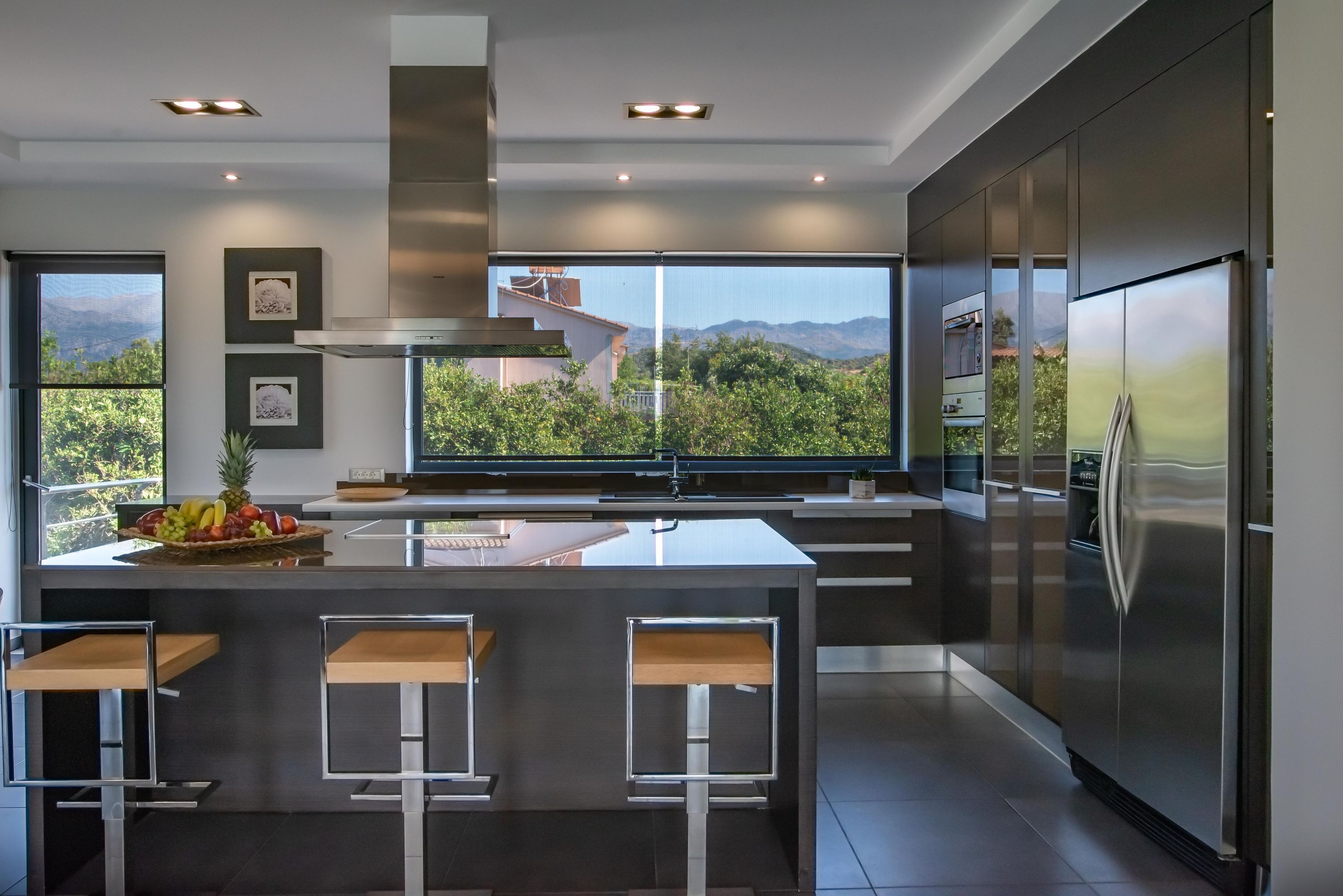 A modern kitchen with a large island, stainless steel appliances, and a view of the mountains.
