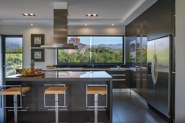 Una cocina moderna con una isla grande, electrodomésticos de acero inoxidable y vistas a las montañas.