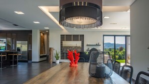 A modern kitchen with a large island, a dining area with a wooden table, and a view of the outdoors. - Villa Vega I Heated Pool Next to Nature (Platanias)