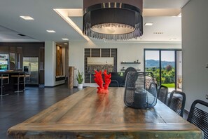 Une cuisine moderne dotée d’un grand îlot central, d’un coin repas avec une table en bois et offrant une vue sur l’extérieur.