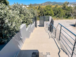 Un sendero conduce a una entrada con portón, con vistas a un paisaje montañoso.