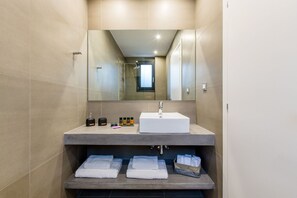 Un baño moderno con un espejo grande, un lavamanos blanco y toallas ordenadas sobre una repisa.