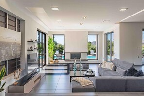 A modern living room with a flat-screen TV, grey sofas, a coffee table, and a fireplace.