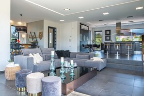 Una sala moderna con un sofá gris, una mesa de centro y jarrones decorativos.