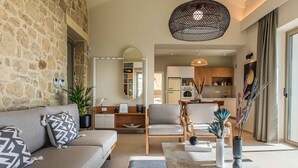 Una sala de estar moderna con una pared de piedra, un sofá, una mesa de centro y una cocina al fondo.